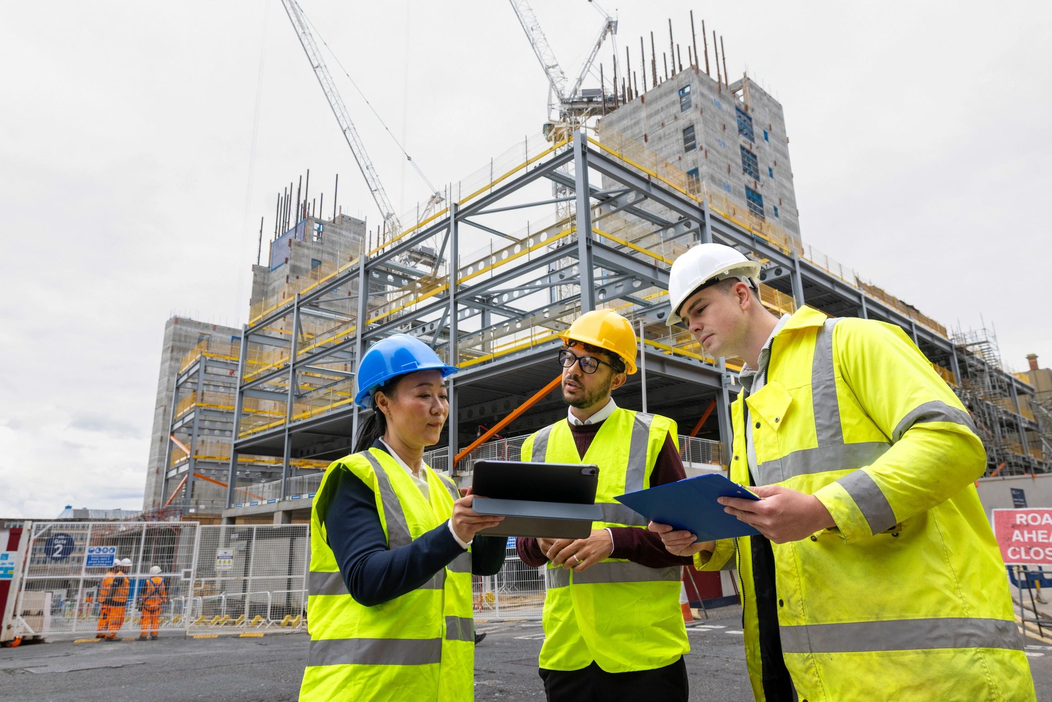 Construction professionals reviewing plans and a tablet on site